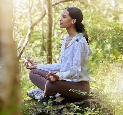 Kvinna sitter i meditation i skogen med slutna ögon